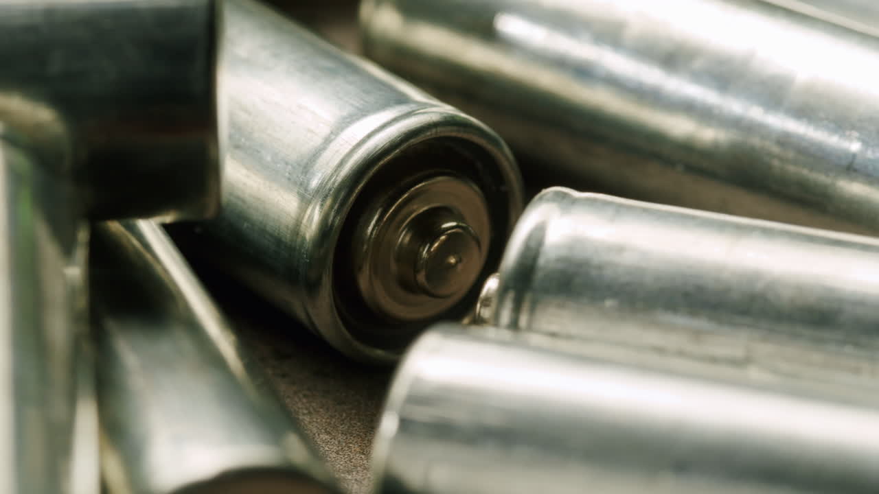 Silver batteries AA and AAA on black background close-up. Double-A battery is a standard size single cell cylindrical dry battery. Batteries are common in portable electronic devices. An AA battery is composed of a single electrochemical cell that may be either a primary battery or a rechargeable ba