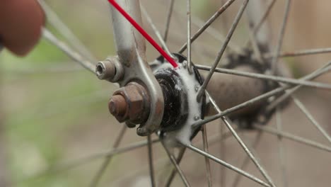 person spraying the wheel hub of a bicycle with a wd-40 lubricant