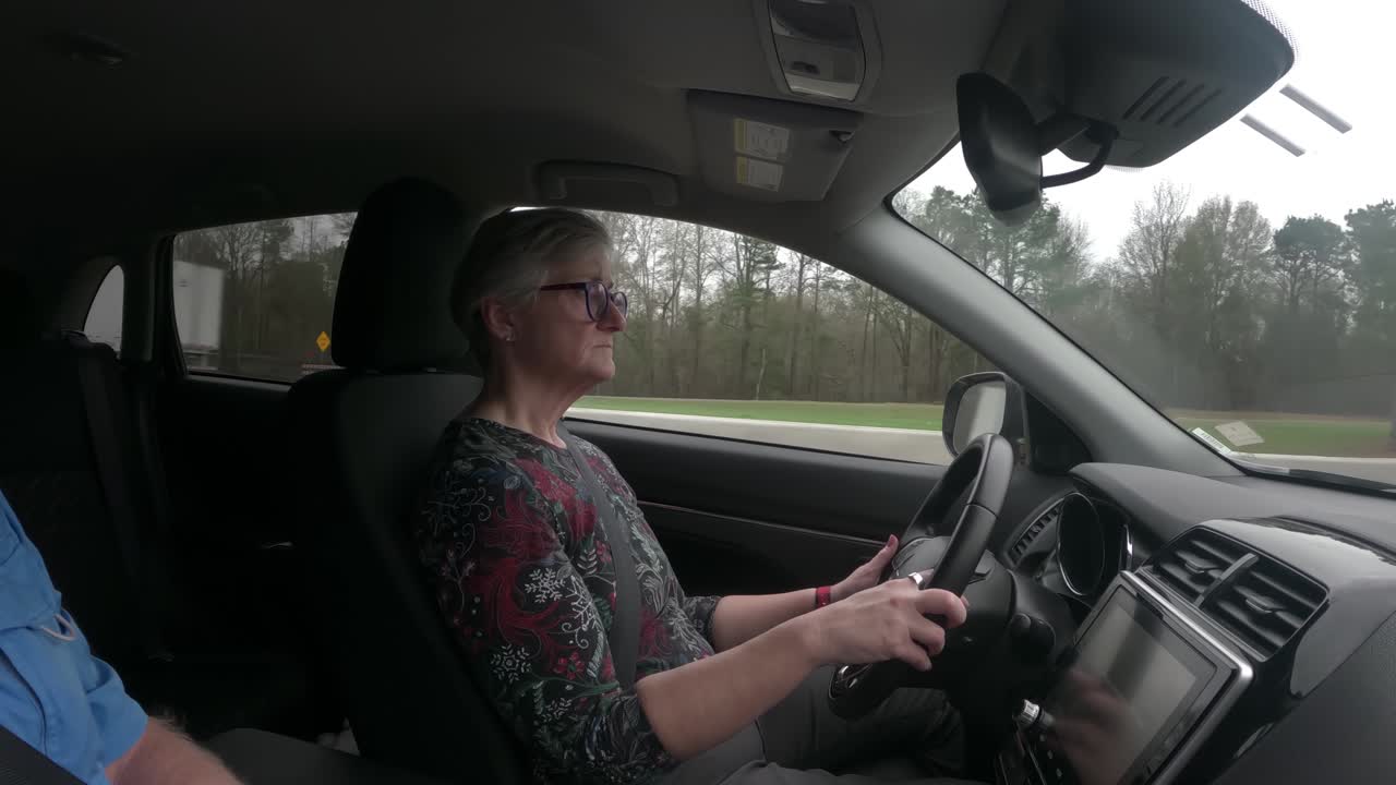 Cute mature woman driving along the highway with another passenger on a winter day road trip