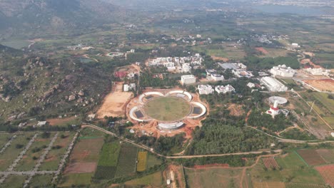 an aerial video shows how agricultural land is being converted to urbanization, which causes deforestation, as a new satellite township is being built close to bangalore's outskirts