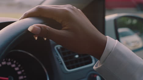 woman driving car with hands on steering wheel to control vehicle in city travelling on the road at rush hour to destination