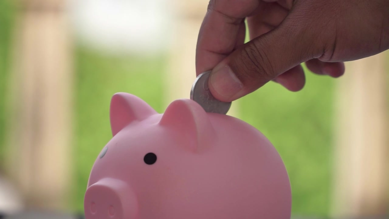 Hand is Saving money in piggy bank, close-up financial concept for investment, banking and wealth growth.