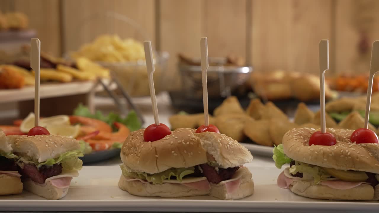 Small burgers with lettuce ham cherry tomato on skewers on a catering tray