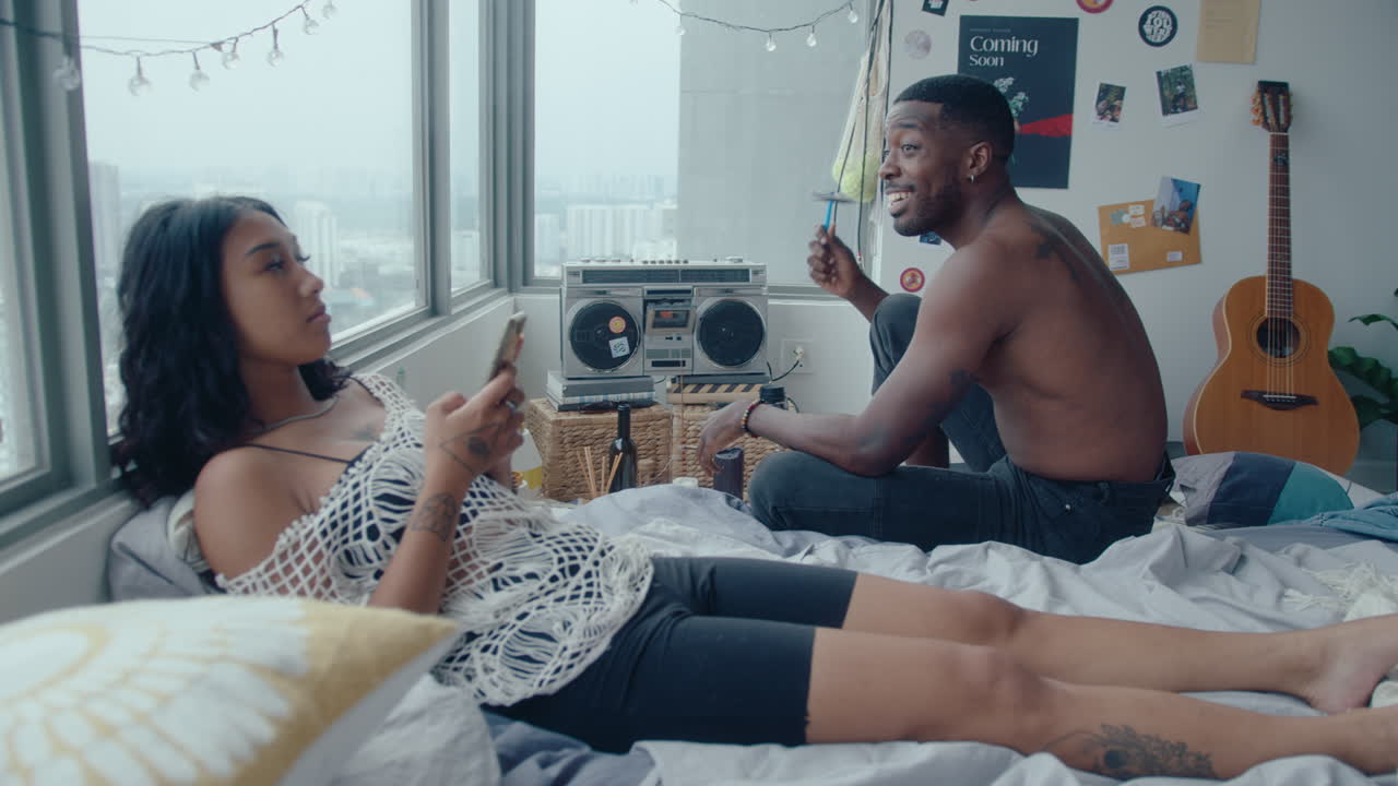 Young Couple Smoking, Chilling, Listening to Music in Bedroom