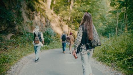 mujer caminando con amigos turistas por el sendero en el bosque