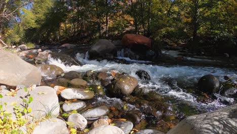 water rushing from a mountain stream forms small waterfalls and rapids between piles of rocks along its path