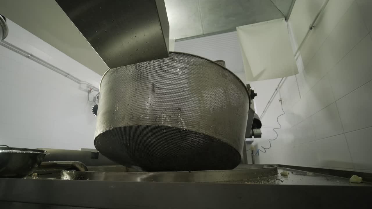 producción de papas fritas y bocadillos. máquina industrial de fritura profunda. las papas fritas se fríen en un cuenco grande con aceite. la línea de producción de la fábrica mueve las papas frias doradas después de freír.