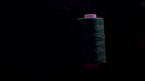 thread spool on bobbin roll color on black background slow motion