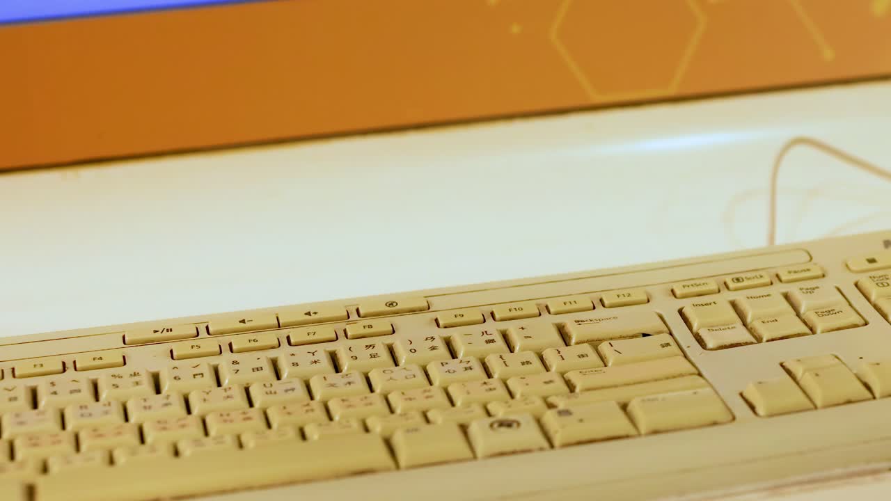 A detailed view of a wired keyboard placed on a light-colored desk surface.