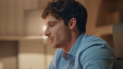 late worker talking web chat sitting dark work desk close up. serious consultant