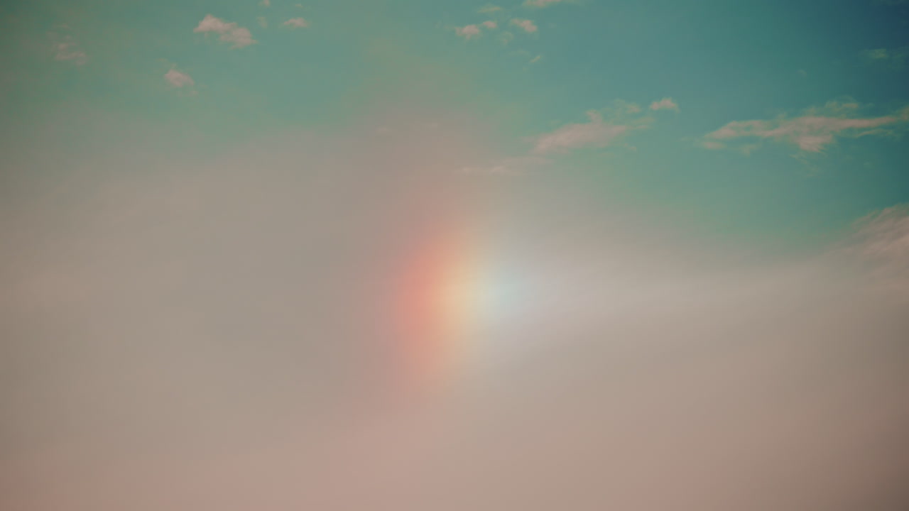 A subtle, soft sky with a faint vertical rainbow or sundog, blending warm and cool tones