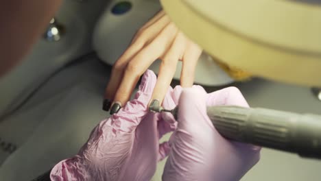 el experto en manicura eliminando el esmalte de uñas de gel laca de las uñas del cliente con un taladro de uñas