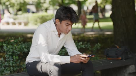 handsome businessman sitting on bench in park and