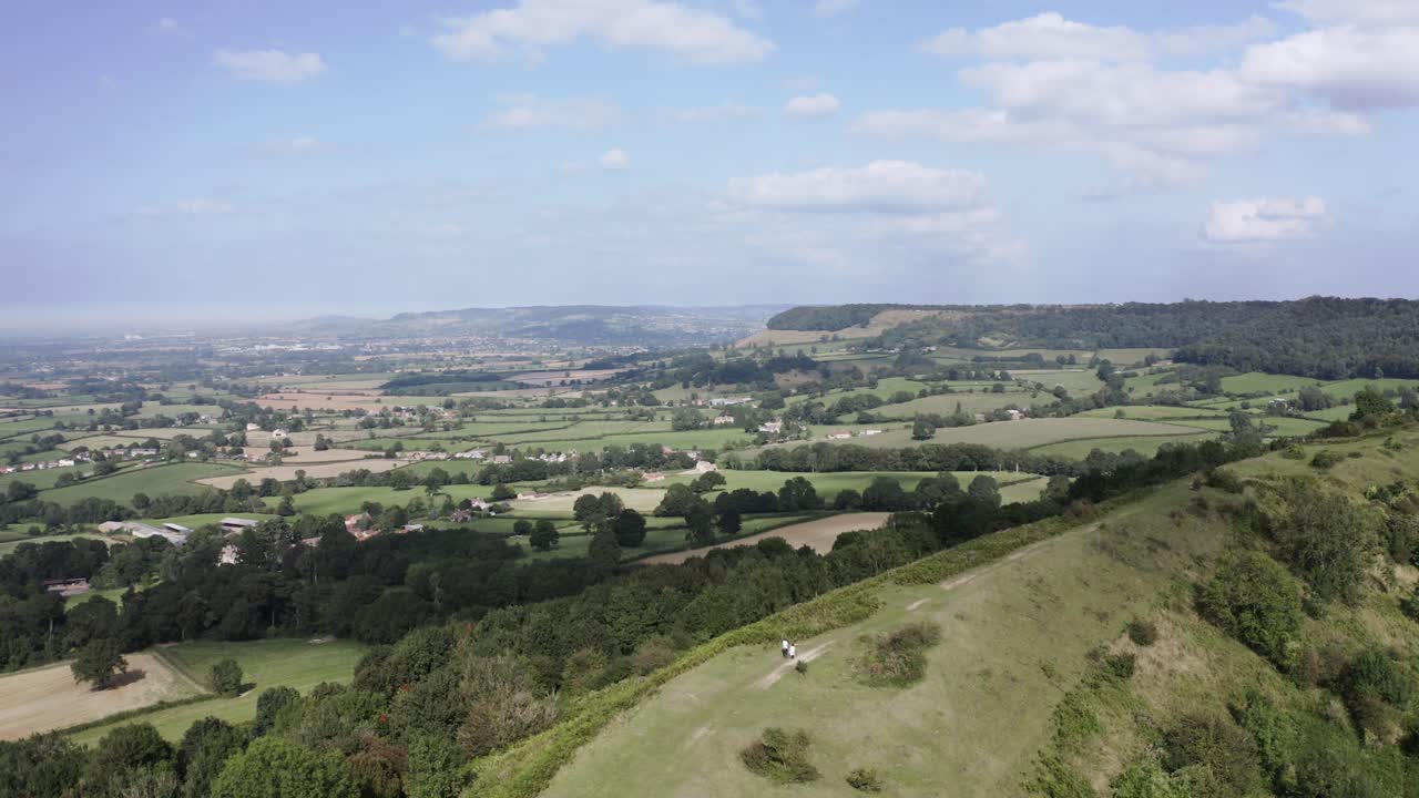 antena - una pareja pasea a su perro en una colina, uley, cotswolds, inglaterra, tiro de ángulo alto