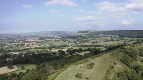 aerial - couple walk their dog on a hill, uley, cotswolds, england, high angle shot