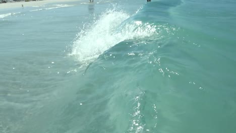 slow motion shot of clear sea water, wave tubing on beach, low level