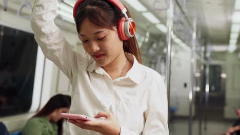 mujer joven usando teléfono móvil en un tren público