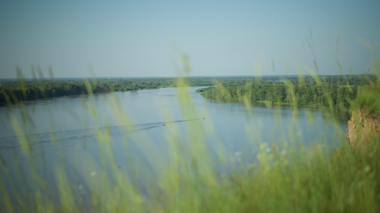 앞면에는 부드럽게 흔들리는 풀이 있고, 배경에는 두 배가 평화롭게 항해하는 평온한 호수가 있습니다. 자연의 부드러움과 물의 평온을 혼합합니다.