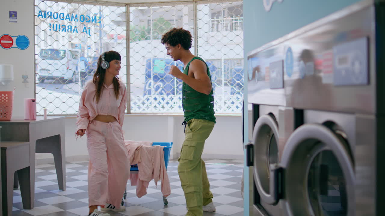 una chica despreocupada bailando con su novio en el servicio de lavandería de la ciudad. amigos felices esperan.