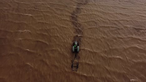 aerial top down of tractor entering river and towing boat out after broke down