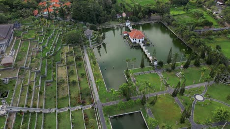 Orbital-drone-view-of-a-Royal-Palace-on-the-island-of-Bali-surrounded-by-water-and-lush-green-landscaped-gardens