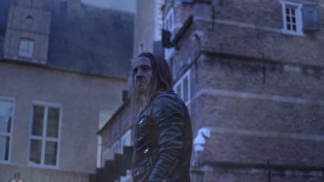 man with long hair and leather jacket conjures fireball in old city