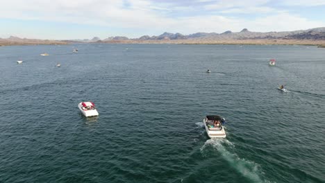 4k aerial drone footage following two boats in the middle of summer in the deserts of arizona and california on lake havasu with friends and families having fun on vacation out on the water