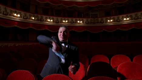 happy actor puts off medical mask and throws it. man in costume sitting in the empty theatrical hall and invites joyfully to come to performance. the end of pandemic.