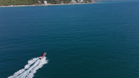 a speedboat cruising through clear blue water near a coastal landscape, aerial view