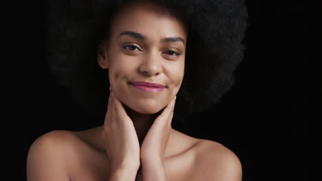 portrait attractive african american woman touching face with hands caressing smooth healthy skin complexion enjoying perfect natural beauty funky afro on black background