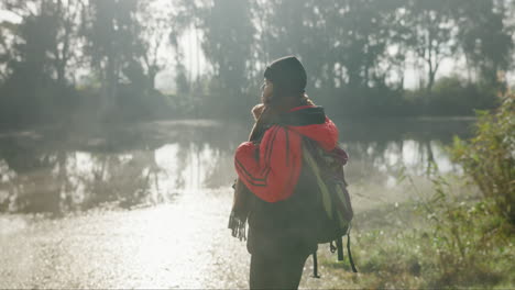 Woman-with-backpack,-fog-and-lake