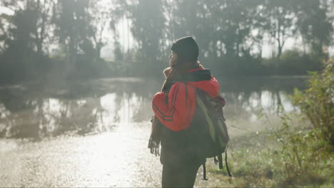 mujer con mochila, niebla y lago