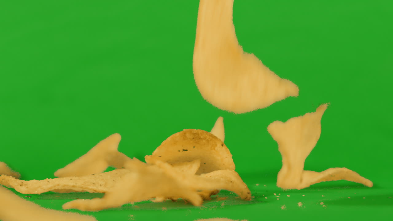 Potato Chips Crisps Falling in Slow Motion on Green Screen Background. Unhealthy Ultra Processed Food Footage Ready to Key. ProRes 4K.