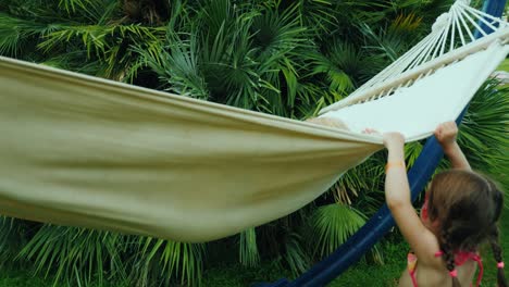 funny children's vacation on the seashore, two sister girls play fun on a hammock in bathing suits