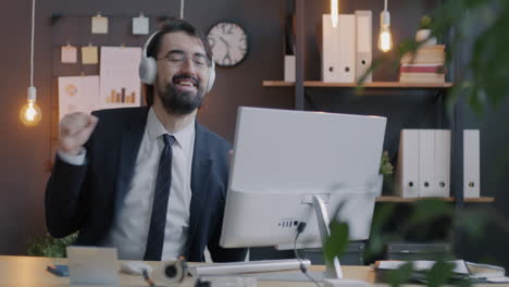 happy businessman listening to music in office