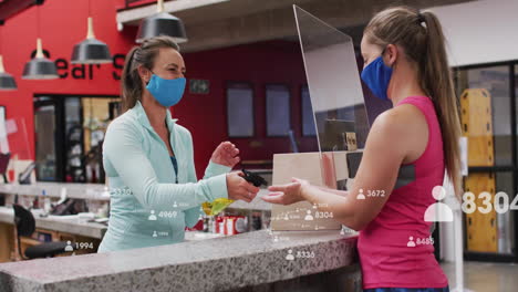 exchanging items at gym counter, women wearing masks with animation overlay