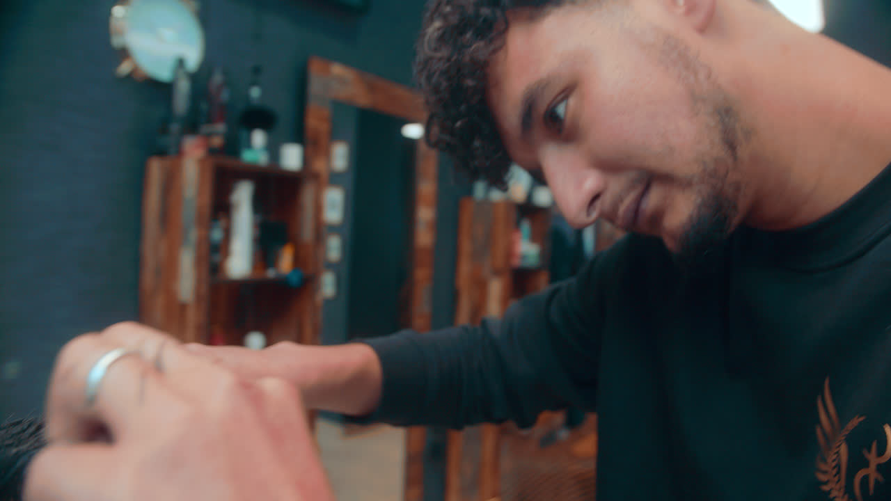 Belo detalhe em close-up de um corte de cabelo clássico com tesoura, feito por um barbeiro profissional indiano numa barbearia durante a manhã.