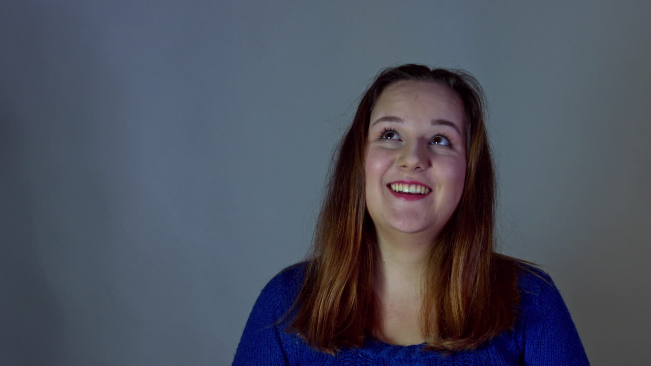 Overweight casual woman in studio looking up on copy space and smiling