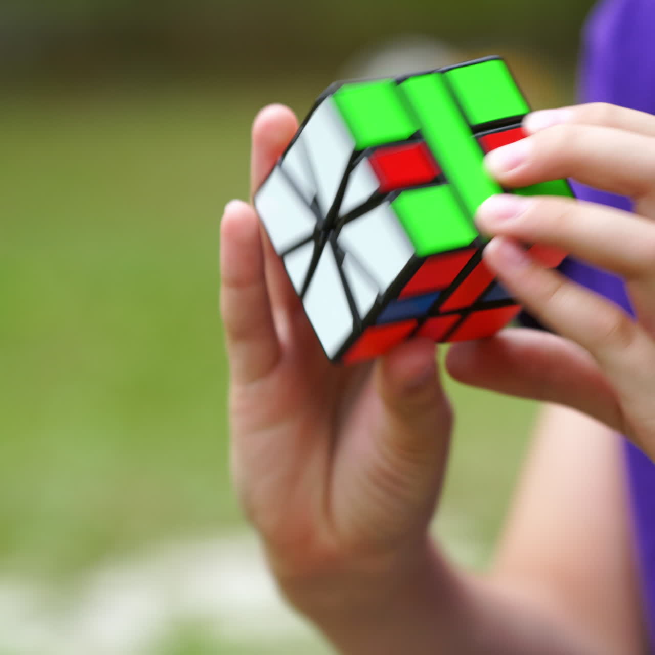 Boy is playing with popular rubik's cube outdoors. Smart kid develops his logic with square intelligent toy of colorful cube. Solution, focus and goal concept.
