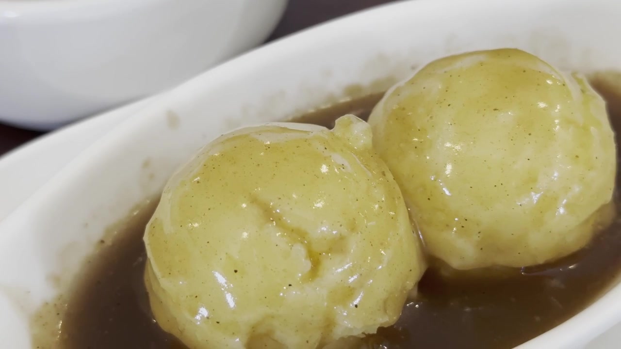 Primo piano di purè di patate cremoso dalla consistenza liscia, splendidamente servito in una ciotola come contorno casalingo e confortante.