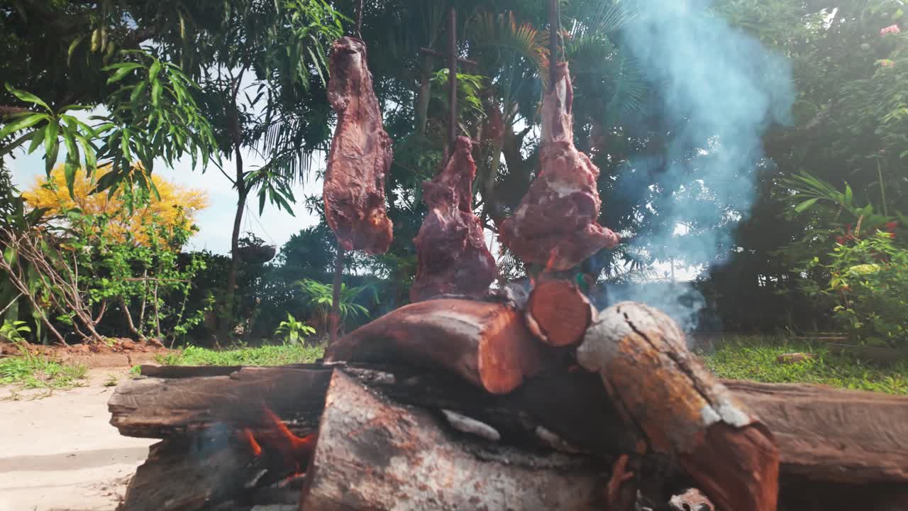 Chef chops raw meat outdoors on wooden board for preparation at rural butcher stall