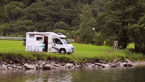 woman is standing with a mug of coffee near the camper rv.