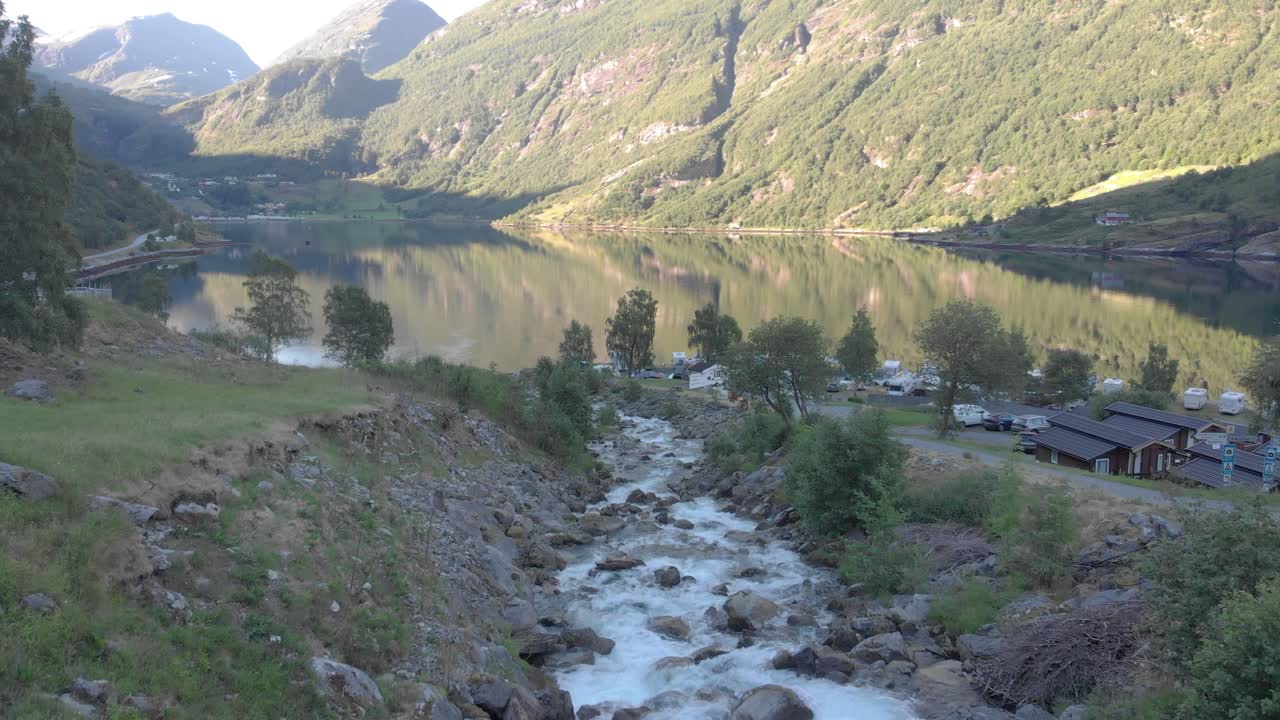el dron está siguiendo una cascada que se convierte en un río y desemboca en el fiordo de geiranger