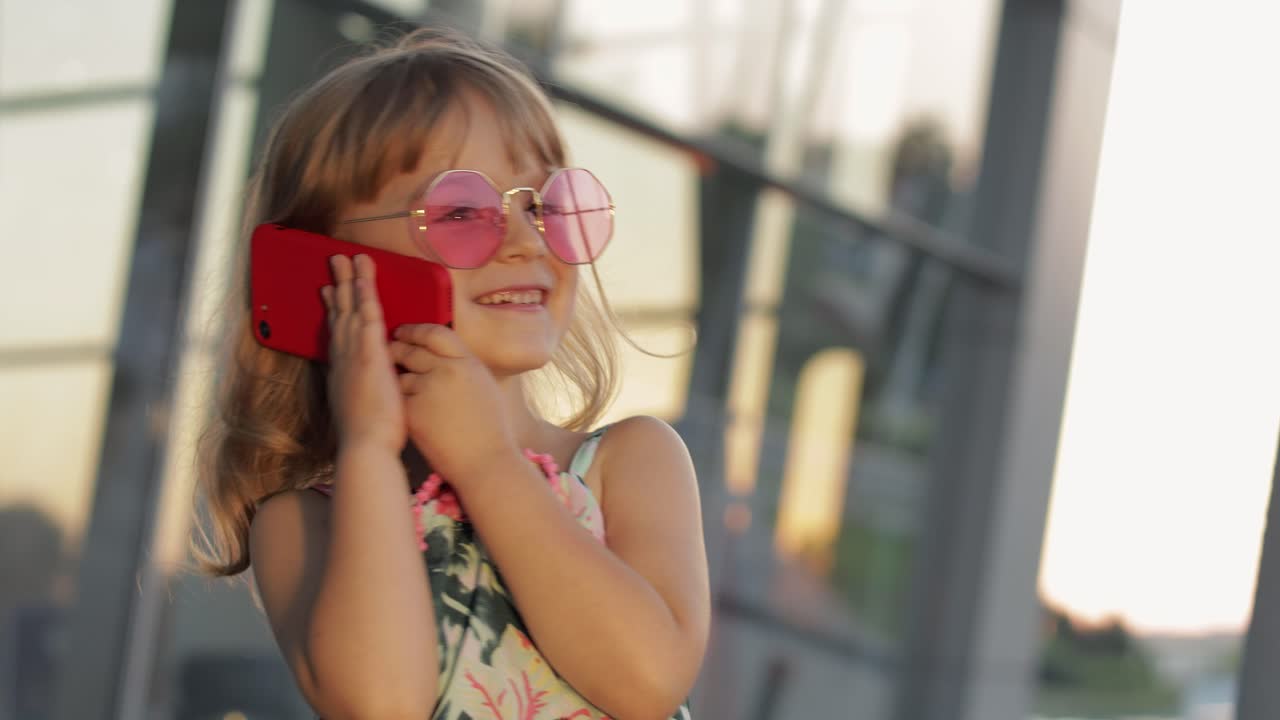 niña turista con gafas de sol de moda usa teléfono. niño usando teléfono inteligente para llamar, hablar. turismo