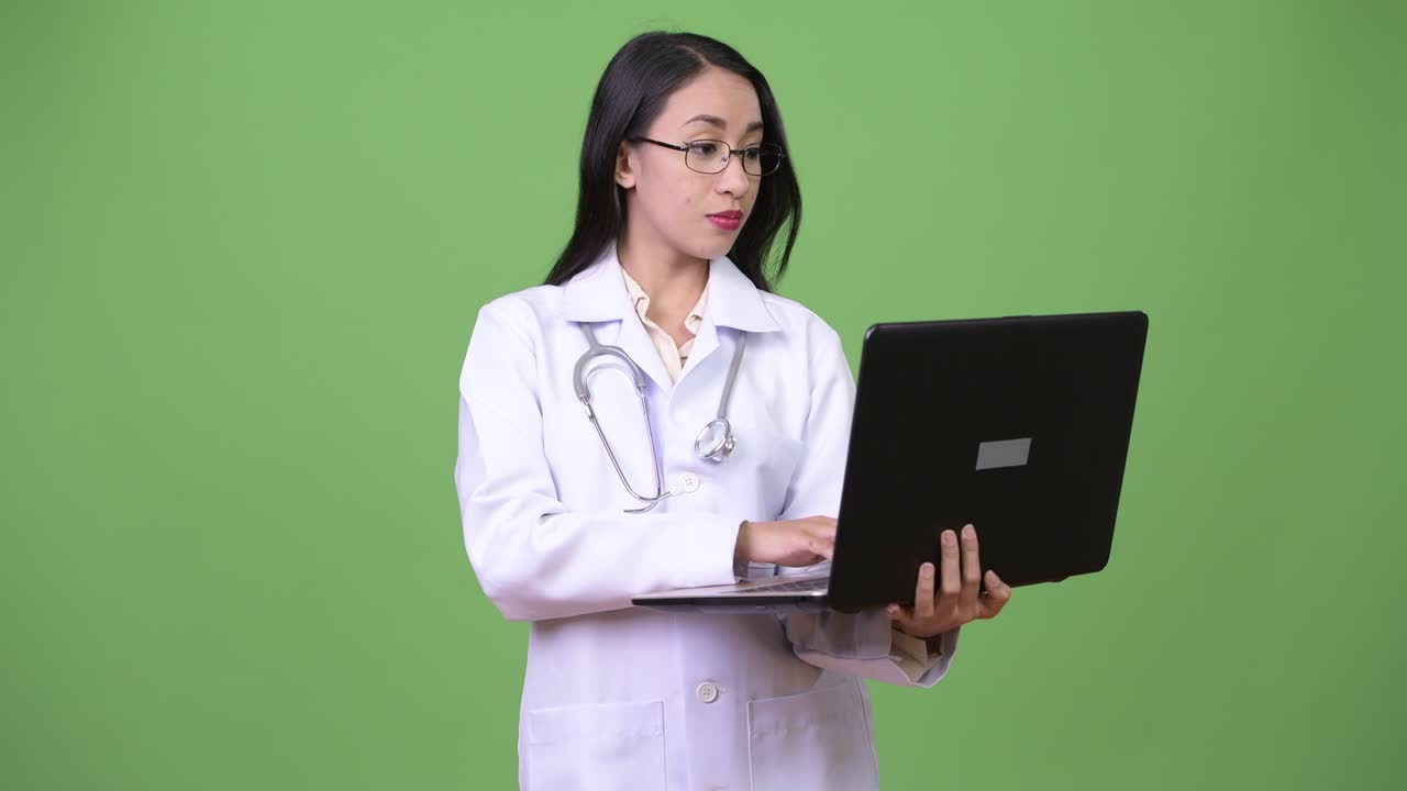 Young beautiful Asian woman doctor using laptop