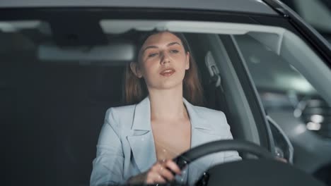 una joven feliz abraza el volante de un auto nuevo y sonríe
