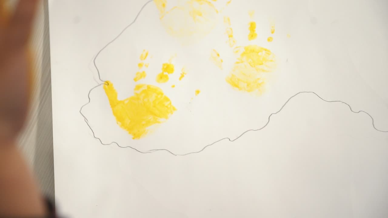 Child making hand prints on paper. Early childhood education. Little painter.