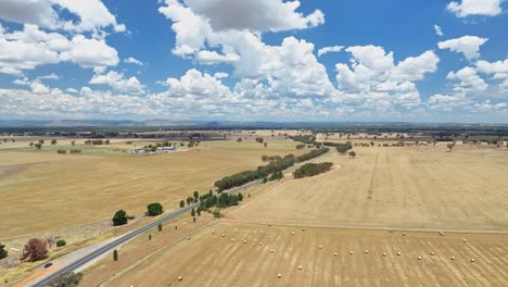 aerial over paddock of round hay bales and across country road in nsw australia