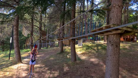 child girl rides zip line at adventure park in woods