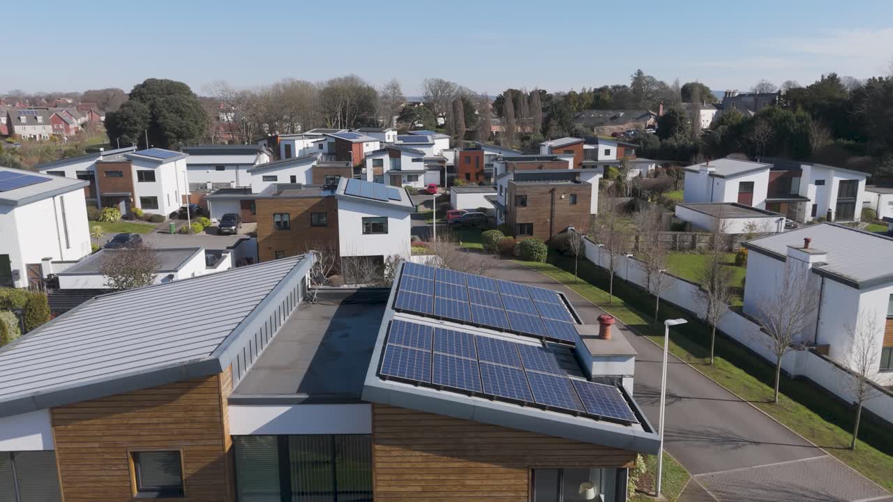 Top-down orbital of dense modern estate of flat-roof timber-clad homes sporting solar arrays, crisp minimal landscaping and energy-efficient contemporary architecture